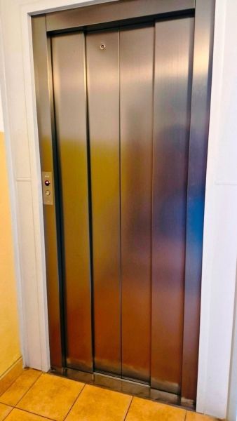 Elevator in the building, studio apartment with tiled floor, visible metal doors.
