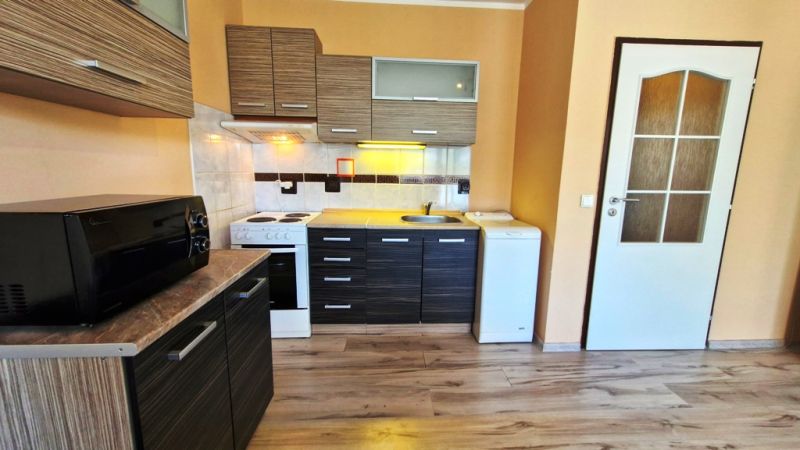 Kitchen unit and appliances in a studio apartment with a wooden decor floor.