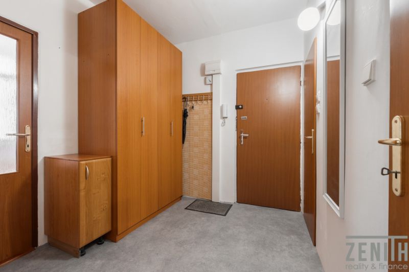 Entrance hallway in a 4-room apartment with wooden cabinets and a coat rack.