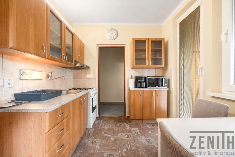 A kitchen in a 4-room apartment with cabinets and appliances; floor with wood decor.