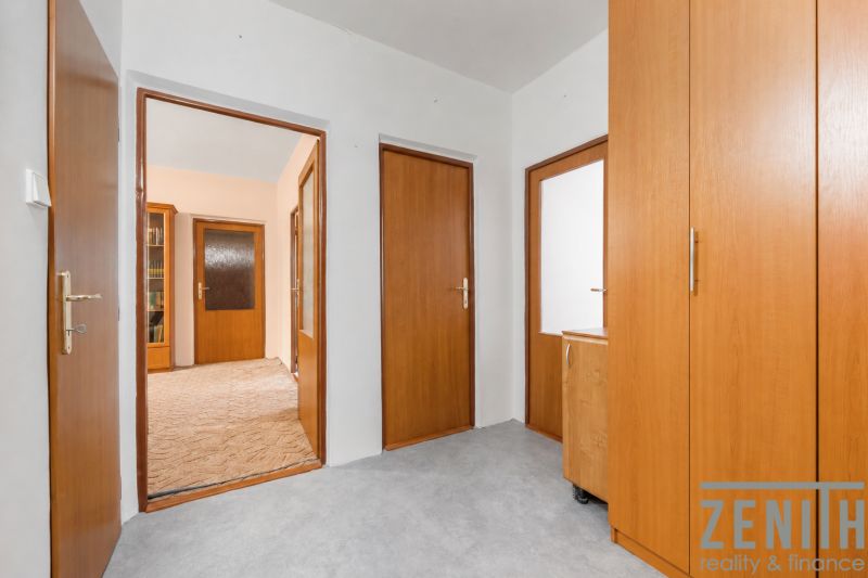 A hallway in a 4-room apartment with wooden doors and built-in wardrobes.