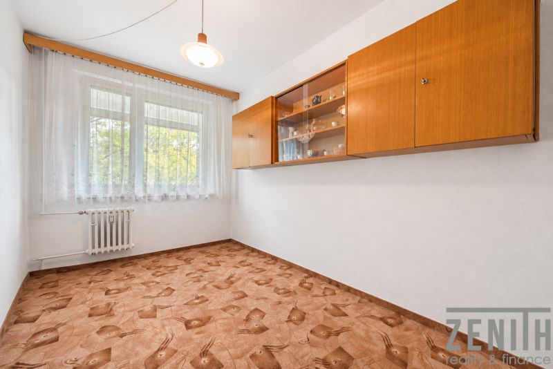 A room in a 4-room apartment with a decorated floor, a window, and a wooden shelf on the wall.