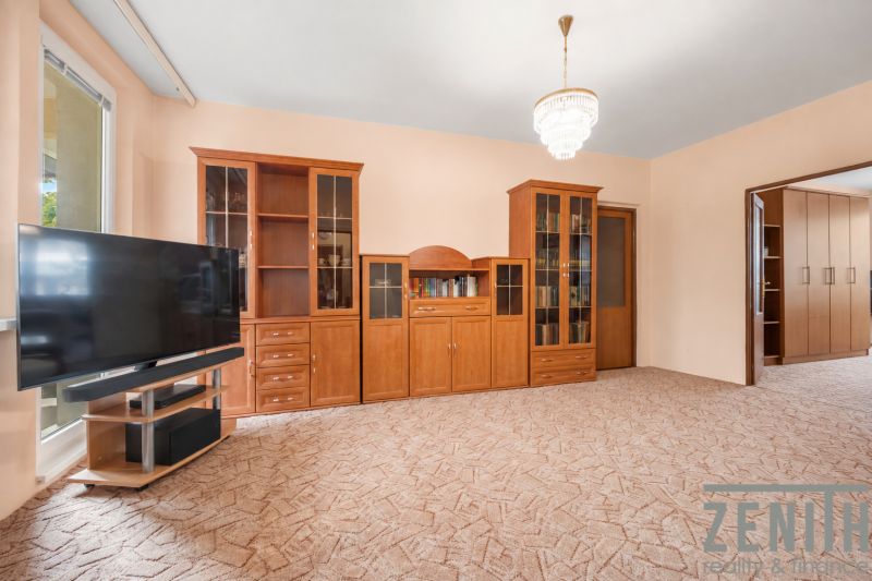 Living room with cabinets and a television in a 4-room apartment on a carpeted floor.