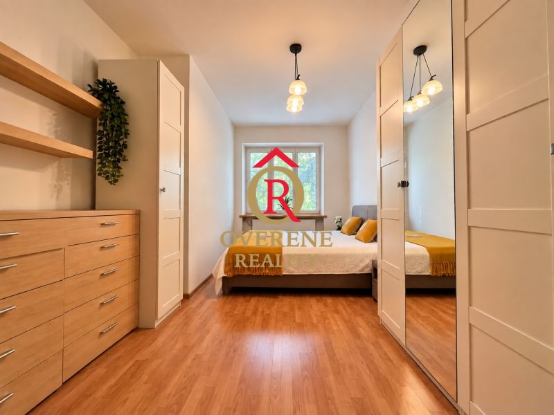 A bedroom in a 2-room apartment with a wood-patterned floor and modern furniture.