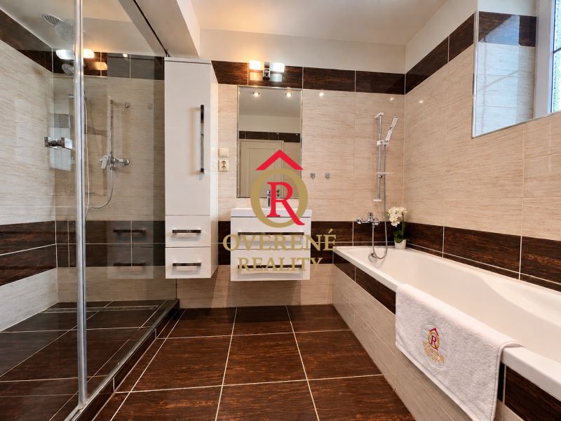 A bathroom in a 2-room apartment with a bathtub, a shower corner, and a floor with a wooden decor.