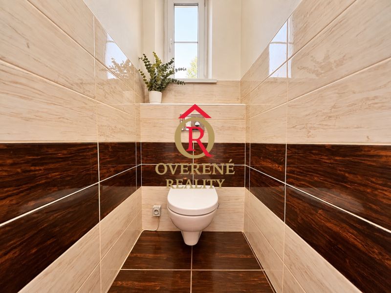 Bathroom in a 2-room apartment with a toilet and dark decor tiles.