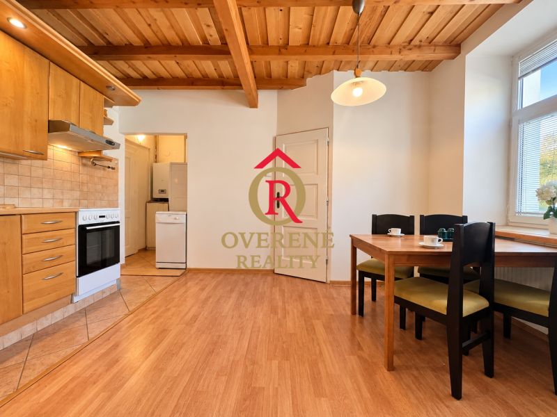 A kitchen with a wooden ceiling, a floor with a wooden decor, a table and chairs in a two-room apartment.