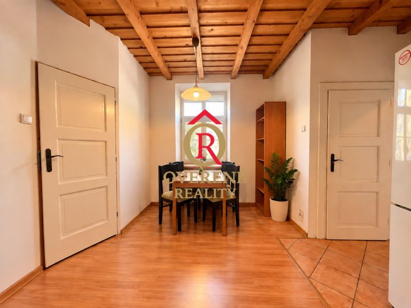 Dining area with a wooden ceiling, table, chairs, and flooring with a wooden decor in a 2-room apartment.