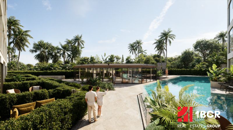 Garden and pool in the apartment complex in Phuket, lined with palm trees and greenery.