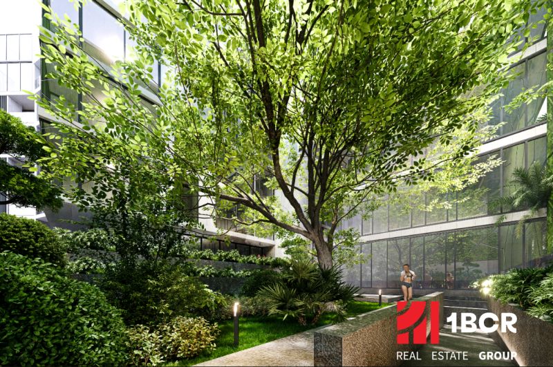 Apartment construction in Phuket with lush greenery and glass facades of buildings.