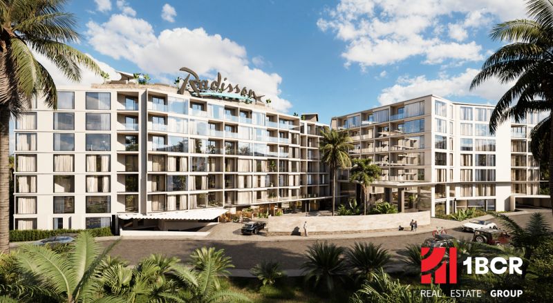 Apartment construction in Phuket with green vegetation, modern architecture, and glass sections.