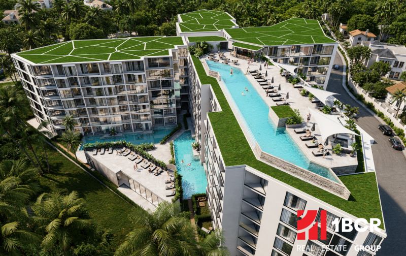 Apartment construction in Phuket with a rooftop pool surrounded by greenery.