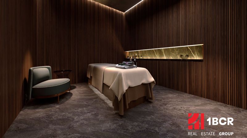 A room with a massage table, a wooden decor floor, and a comfortable armchair. Apartment construction.