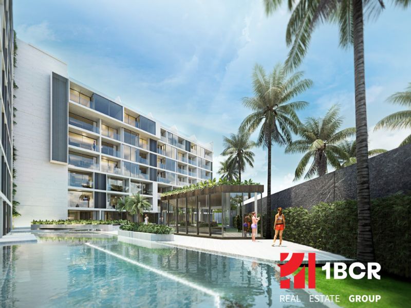 Apartment construction in Phuket with a pool and palm trees in the background.