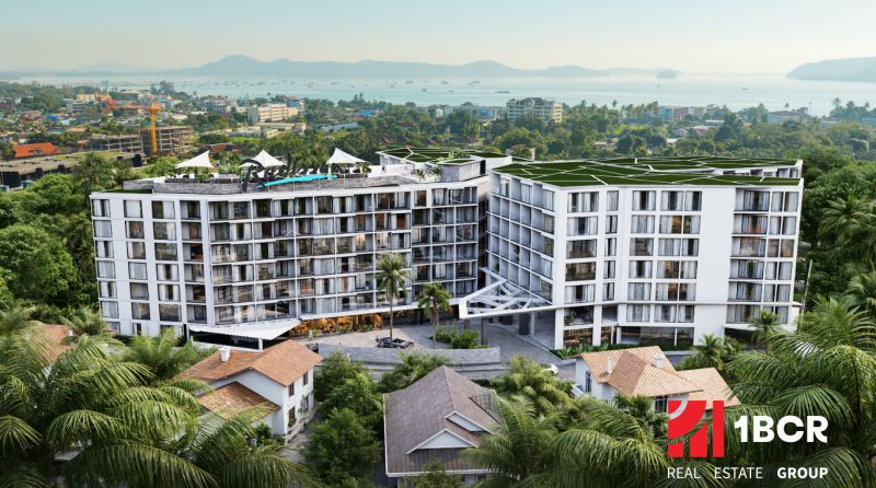 Construction of apartments in Phuket with a view of the sea and surrounding palm trees.
