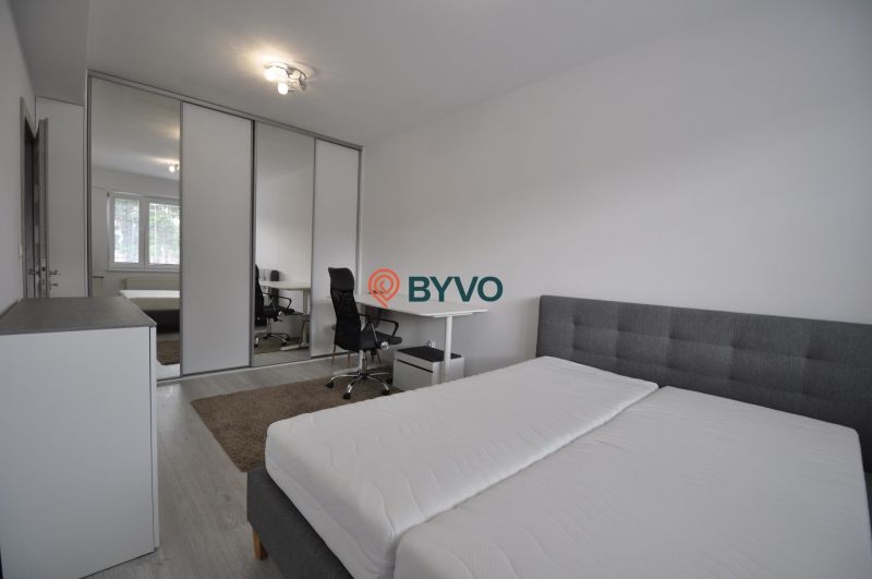 A bright bedroom with a work corner and built-in wardrobes in a 2-room apartment.
