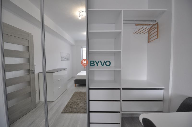 White built-in wardrobe with shelves and mirror in a 2-room apartment.