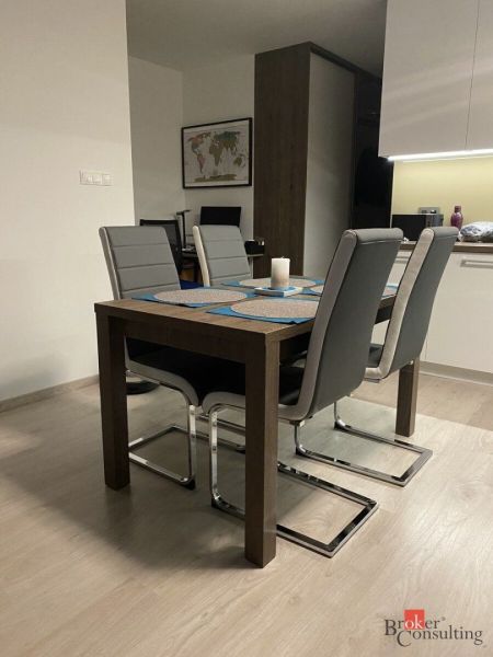 Dining table with four gray chairs in a 2-room apartment, floor with wood decor.