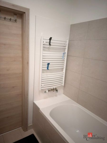 A bathroom with a bathtub and a ladder radiator in a 2-room apartment.