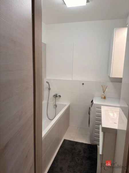 Bathroom in a 2-room apartment with a bathtub, washing machine, and sink.