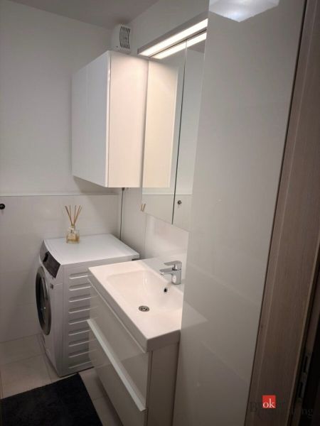 A bathroom with a washing machine and a sink in a 2-room apartment.
