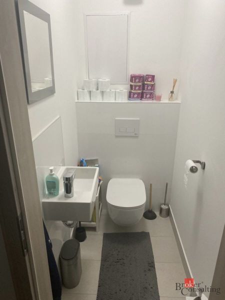 Compact bathroom in a 2-room apartment with a toilet, sink, and storage space.
