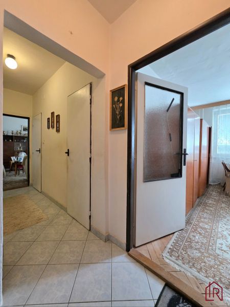 A hallway in a 2-room apartment with a transition to a room with a wooden decor floor.