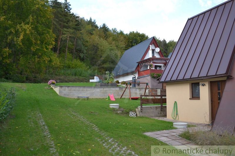 A cottage in Nižná Polianka with two houses, a garden, and a forest in the background.