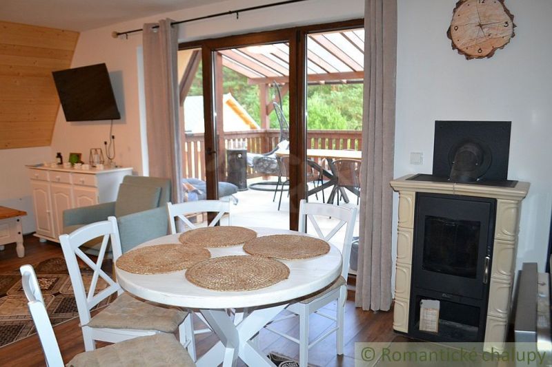 The interior of the cabin with a fireplace, dining table, television, and access to the terrace.