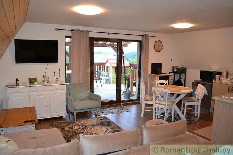 Living room in a cottage with a terrace, dining table, and wooden decor flooring.