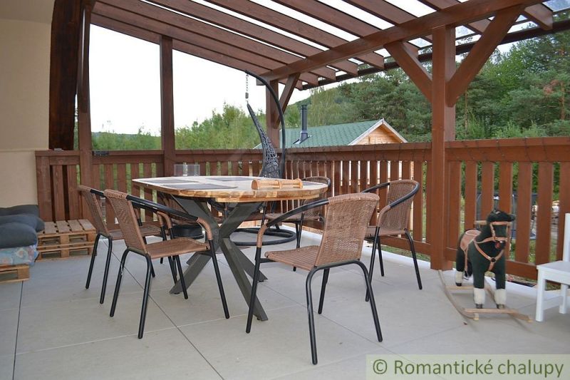 The terrace of the cottage in Nižná Polianka with a wooden table and chairs under a covered pergola.