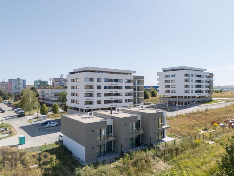 A family house in Poprad near modern apartment buildings and greenery.