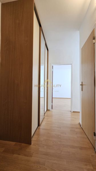 A hallway in a one-room apartment with a wooden decor floor and a built-in wardrobe.