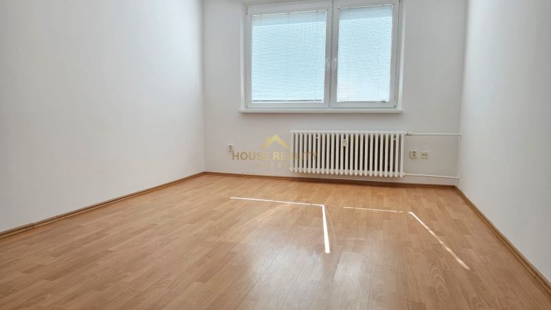 Empty room with wood-patterned flooring, radiator, and window with blinds.