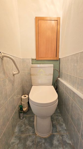 A bathroom with a toilet bowl and a storage cabinet in a studio apartment.