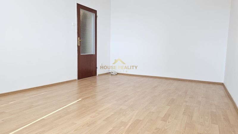 An empty room with white walls and a floor with a wooden decor in a studio apartment.