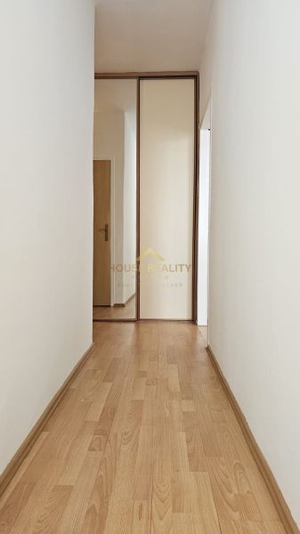 A hallway in a one-room apartment with a wooden decor floor and a built-in wardrobe.