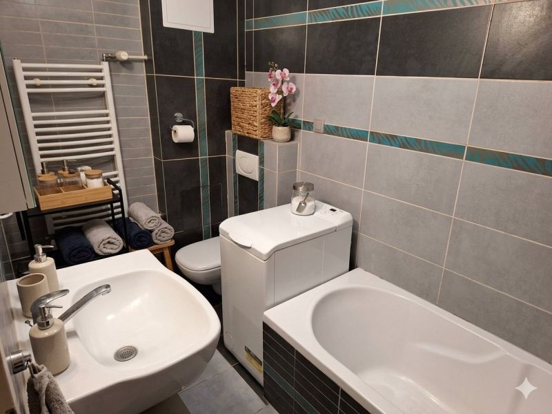 Bathroom in a 2-room apartment with a bathtub, washing machine, sink, and toilet.