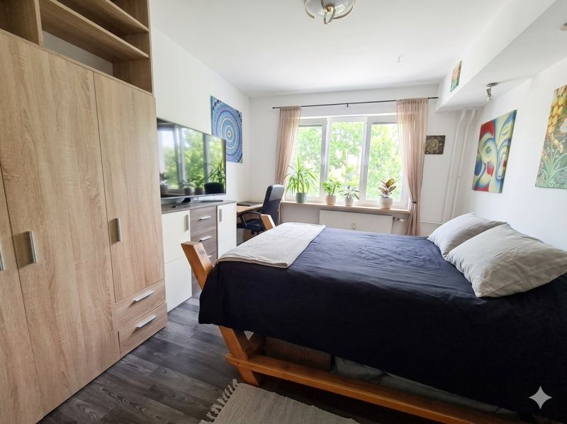 Bedroom in a 2-room apartment with a bed, wardrobe, and wooden decor flooring.