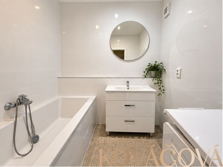 A bathroom with a mirror and a bathtub in a 4-room apartment with decorative tiles.