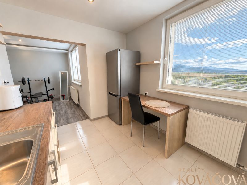 A kitchen with a window and an exercise corner in a 4-room apartment with a wooden decor floor.