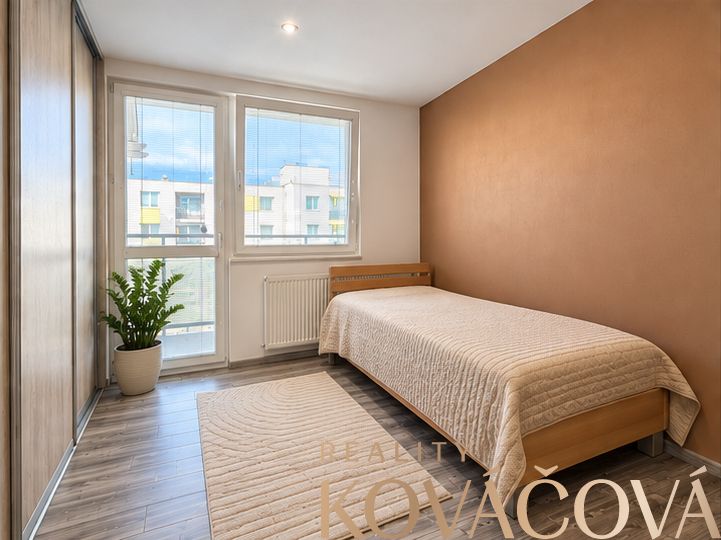 A room of a 4-room apartment with a wooden decor floor and a bed.