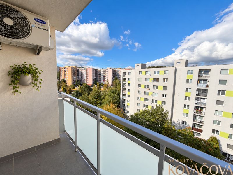 View from the balcony of a 4-room apartment on Halalovka in Trenčín, houses and greenery.