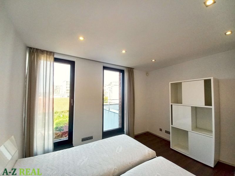 A bedroom in a 4-room apartment with large windows and a wooden decor floor.