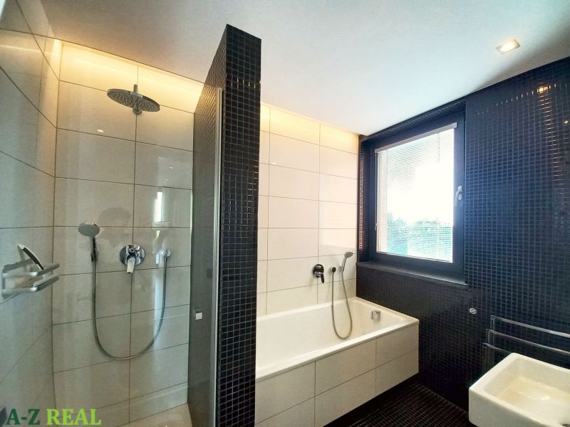 A bathroom in a 4-room apartment with a bathtub, shower, and window.