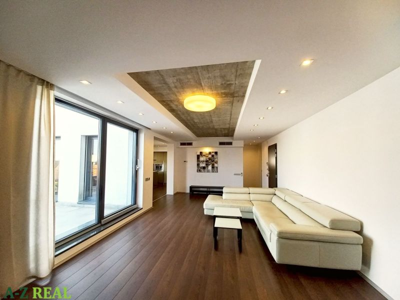 Living room in a 4-room apartment with a glass wall and wooden decor flooring.
