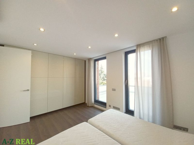 A bedroom in a 4-room apartment with wood-patterned flooring and large windows.