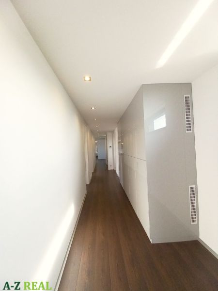 A hallway with built-in wardrobes and a wooden decor floor in a 4-room apartment.