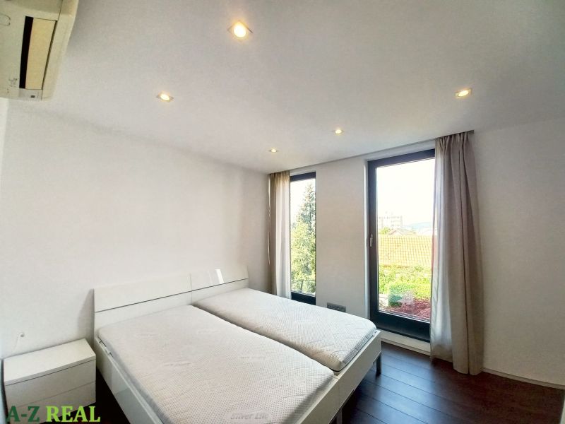 A bedroom with light-colored walls, a double bed, and a wood-patterned floor in a four-room apartment.