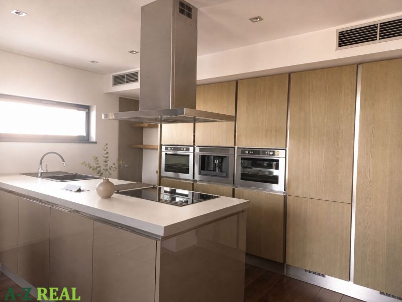A 4-room apartment kitchen with an island and appliances, floor with wood decor.